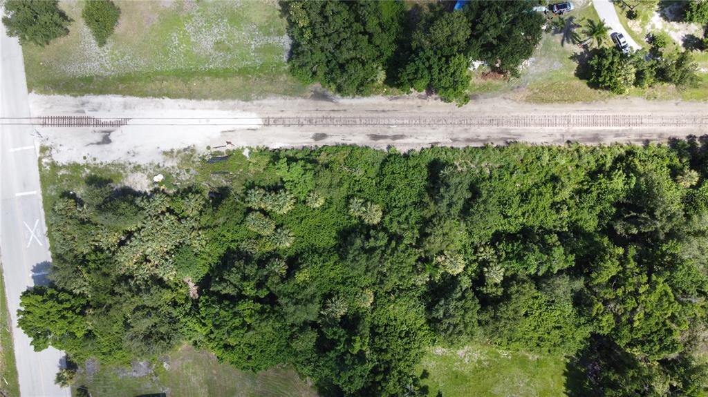 An aerial view shows a wooded lot adjacent to a railroad track and a paved road — CLEVELAND AVENUE, PUNTA GORDA, FL