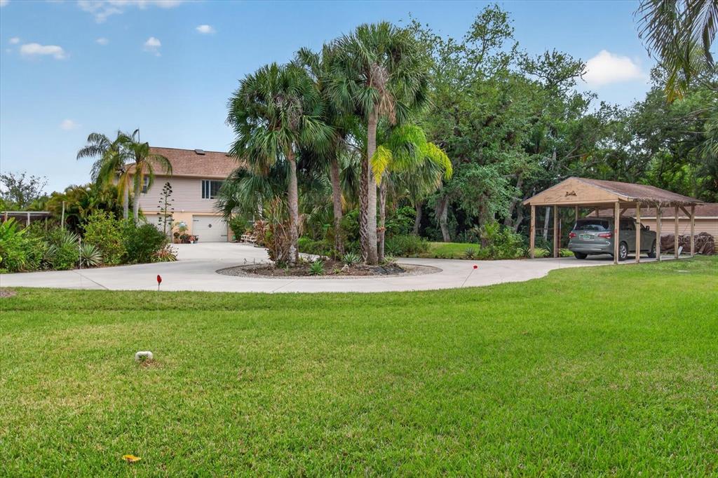 A two-story house with a circular driveway, palm trees, and a detached wooden carport — 4190 STROMBUS ROAD, VENICE, FL