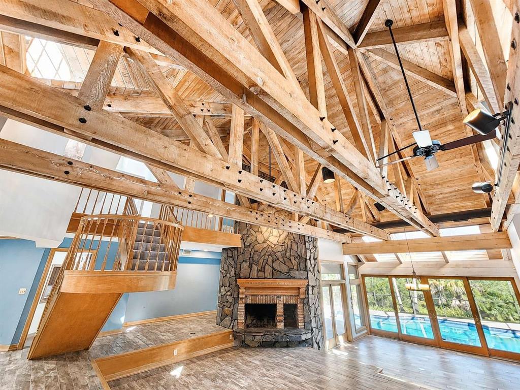 A spacious room with exposed timber trusses, a stone fireplace, and an indoor swimming pool — 3522 SHORELINE CIRCLE, PALM HARBOR, FL