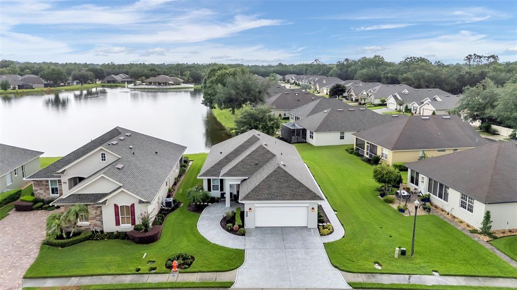 An aerial view shows two suburban houses with gray roofs and green lawns near a lake — 2309 LAKE JAMES WAY, LAKELAND, FL