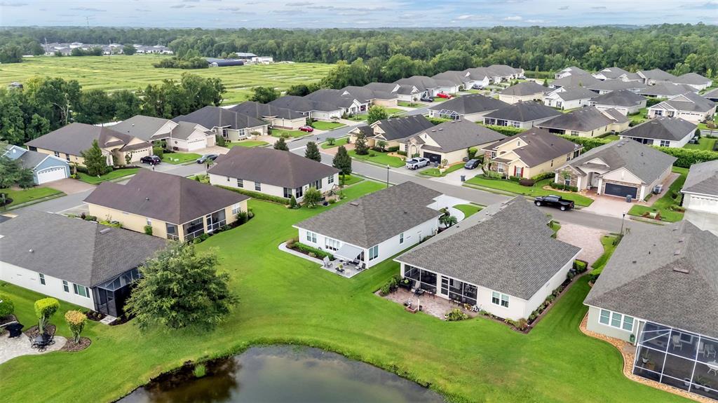 An aerial view shows a suburban neighborhood with single-family homes surrounding a small pond — 2309 LAKE JAMES WAY, LAKELAND, FL