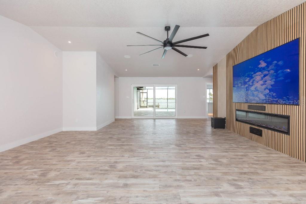 A living room features wood-look flooring, a slatted wood accent wall, and a sliding glass door — 306 BUTTONWOOD LANE, LARGO, FL