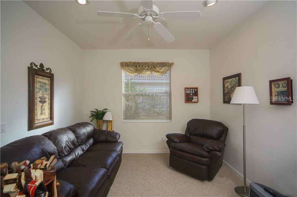 A living room features a brown leather sofa, a matching armchair, and a window with valance — 8218 EAGLE ISLES PLACE, BRADENTON, FL
