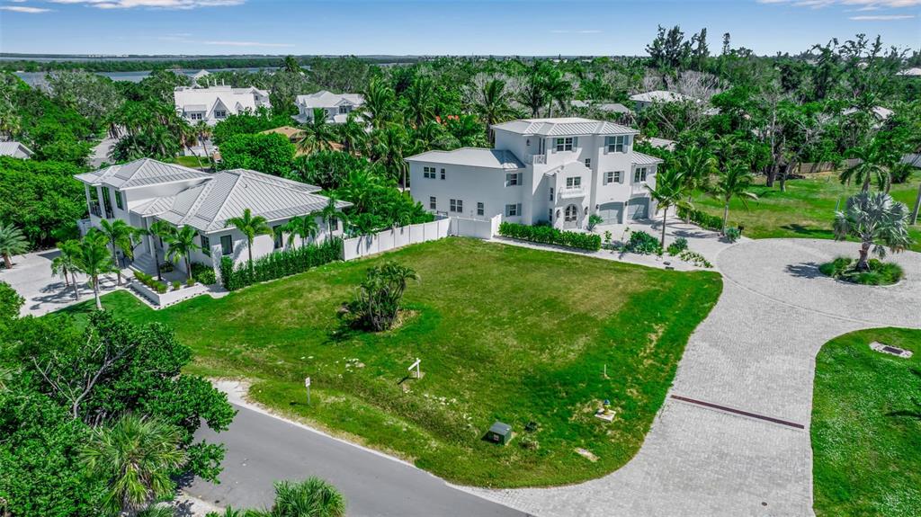 An aerial view shows a vacant grassy lot situated between two large white houses — 610 HIBISCUS WAY, LONGBOAT KEY, FL