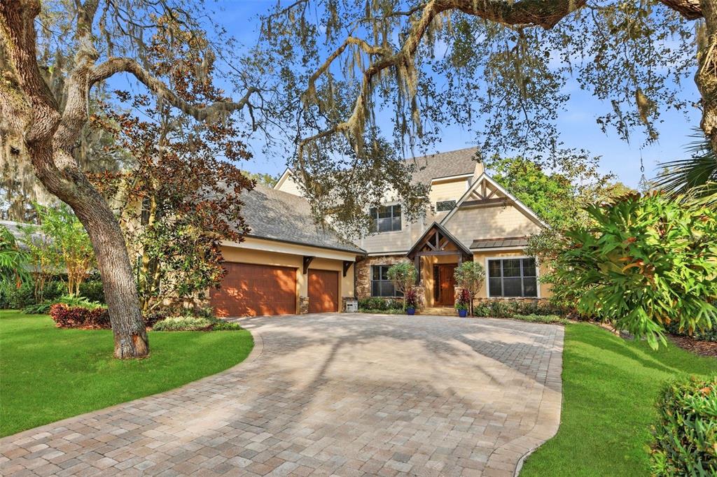A stone-accented entryway features a wooden front door, a covered porch, and two potted plants — 713 MAIN STREET, WINDERMERE, FL