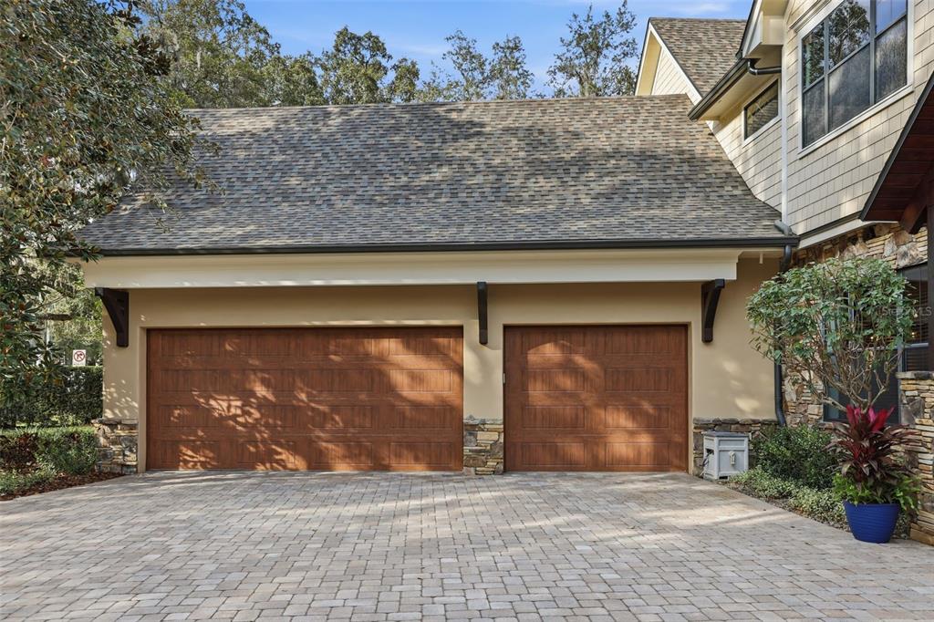 A two-story house with a paved driveway, a three-car garage, and large oak trees — 713 MAIN STREET, WINDERMERE, FL