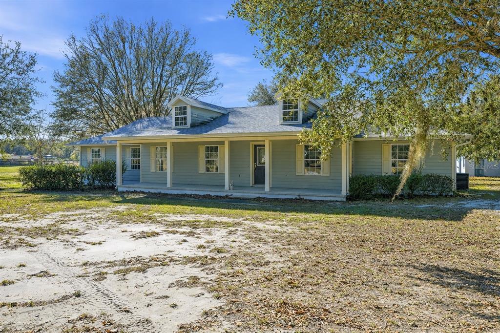 A single-story light green house with a covered front porch and two roof dormers — 36841 RESERVE DRIVE, EUSTIS, FL