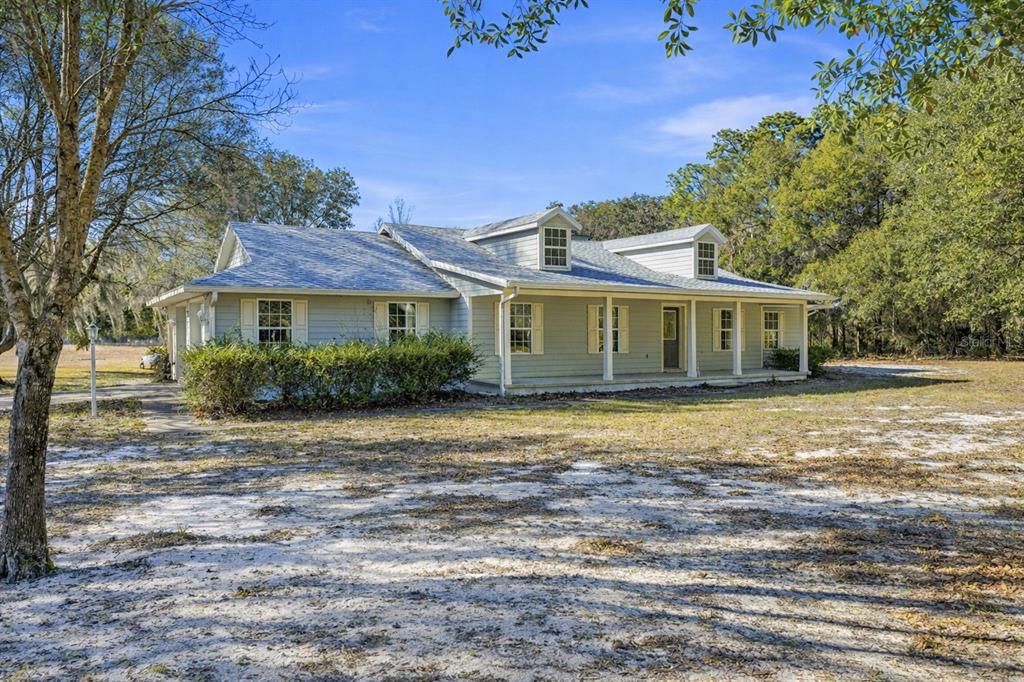 A light green, single-story house with a metal roof and a covered front porch — 36841 RESERVE DRIVE, EUSTIS, FL