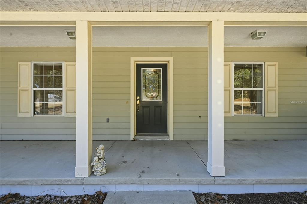 A covered front porch features a dark front door, two windows with shutters, and columns — 36841 RESERVE DRIVE, EUSTIS, FL