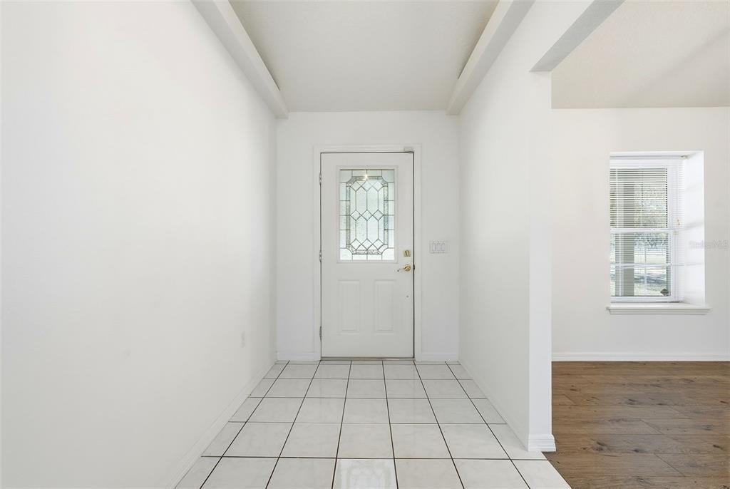 An entryway features white tiled floors, a white front door with glass, and white walls — 36841 RESERVE DRIVE, EUSTIS, FL