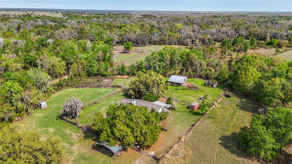 An aerial view shows a house with a metal carport, a shed, and a barn — 32400 TAYLOR GRADE ROAD, DUETTE, FL