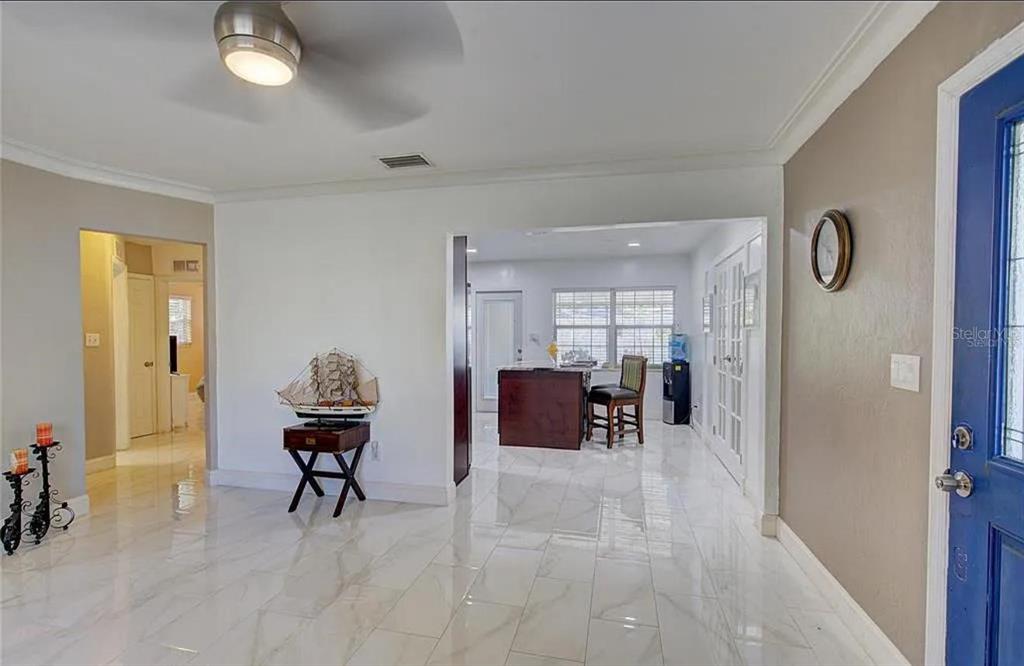 An entryway with white marble-look tile floors leads into a dining area with a desk — 1008 CHESTER DRIVE, CLEARWATER, FL