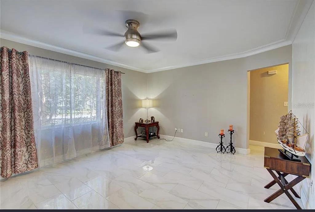 A living room with white marble tile flooring, a ceiling fan, and a window with curtains — 1008 CHESTER DRIVE, CLEARWATER, FL