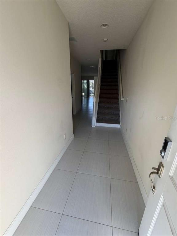 A tiled entryway leads to a carpeted staircase and a view of the living area — 17505 PLACIDITY AVENUE, CLERMONT, FL