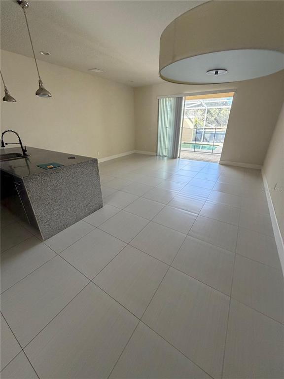 An open-concept kitchen and living area features tile flooring, granite countertops, and a sliding door — 17505 PLACIDITY AVENUE, CLERMONT, FL