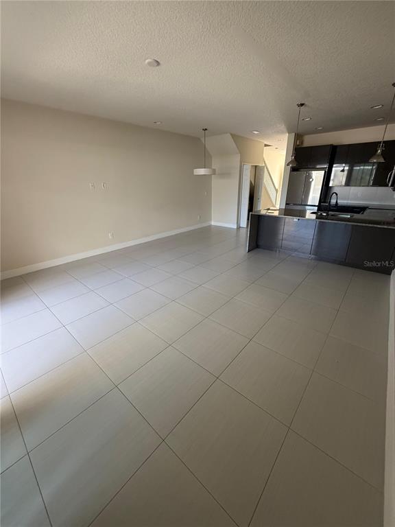 An open-concept living area features large light-colored floor tiles and a modern kitchen with dark cabinetry — 17505 PLACIDITY AVENUE, CLERMONT, FL
