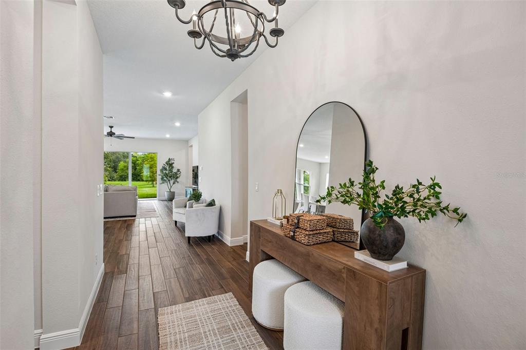 A bright entryway features a wood console table, arched mirror, and wood-look tile flooring — 7510 ASHBROOKE PINE LOOP, ODESSA, FL