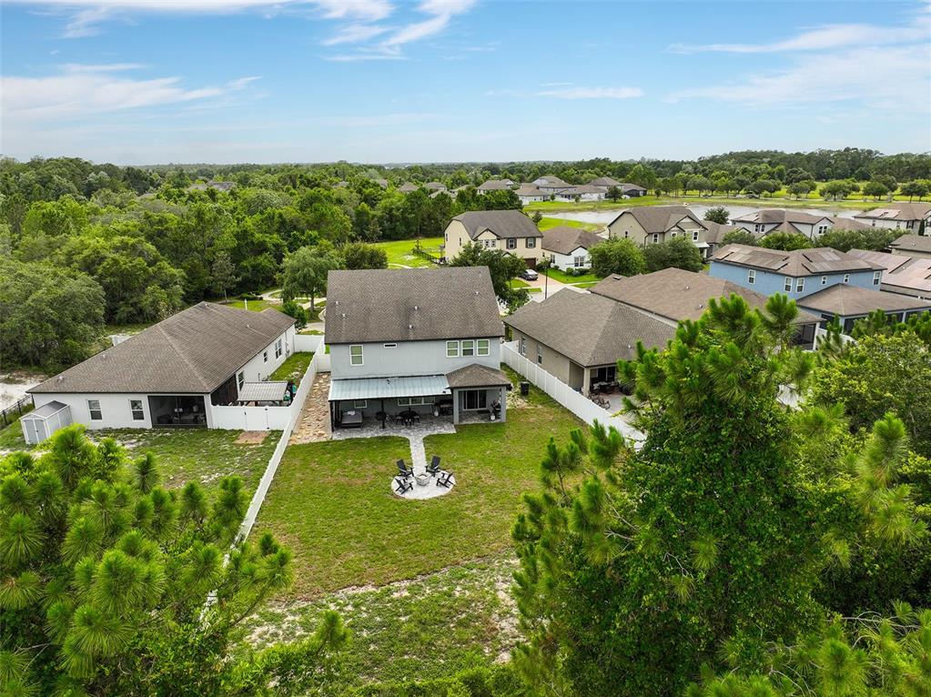 An aerial view shows a two-story house with a fenced backyard, patio, and fire pit — 3481 MIDDLEBROOK PL, ST CLOUD, FL