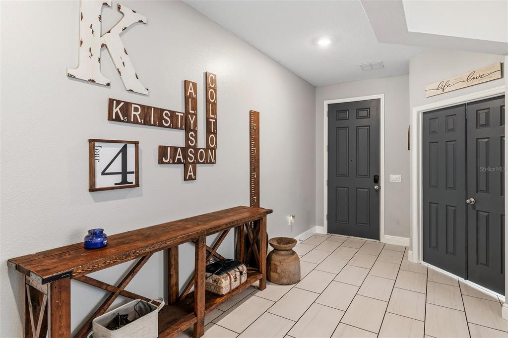 A foyer features a wooden console table, gray doors, and wall-mounted Scrabble-style name tiles — 3481 MIDDLEBROOK PL, ST CLOUD, FL