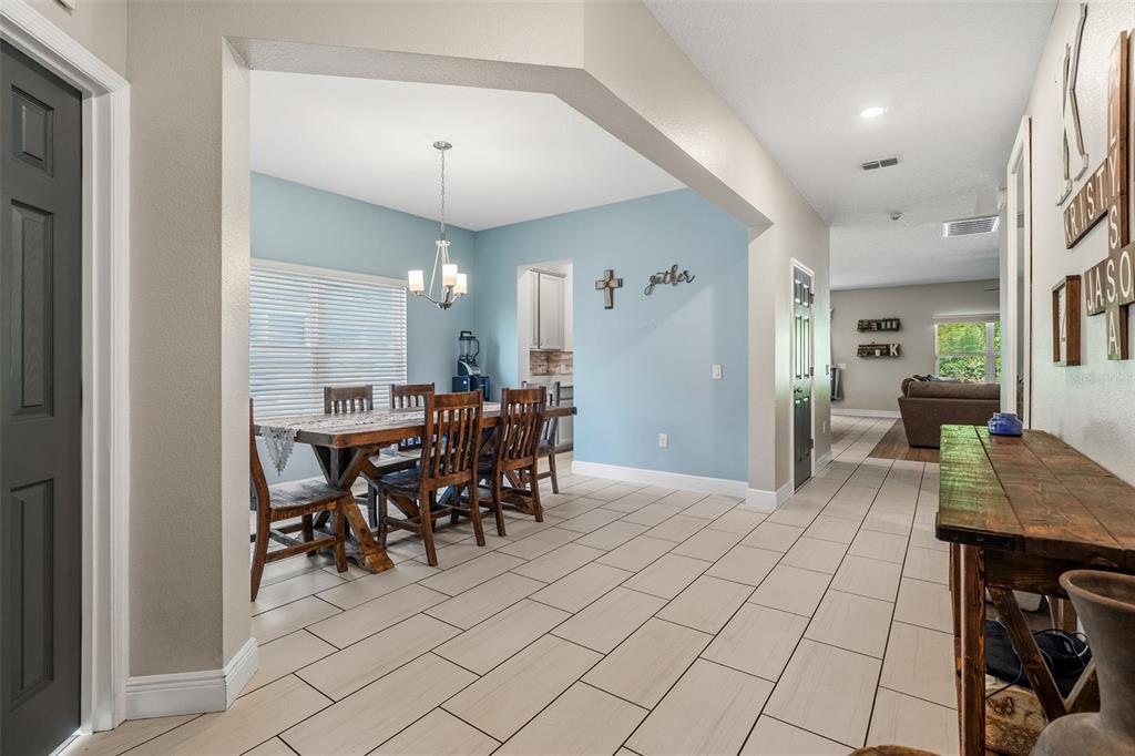 A dining area with a wooden table and chairs sits adjacent to a tiled hallway — 3481 MIDDLEBROOK PL, ST CLOUD, FL