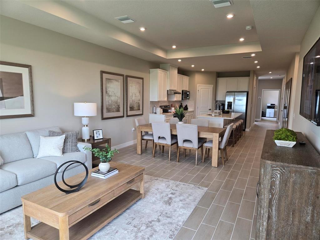An open-concept living and dining area features light wood furniture, tile flooring, and white cabinetry — 18857 EMERALD SUMMIT DRIVE, SPRING HILL, FL