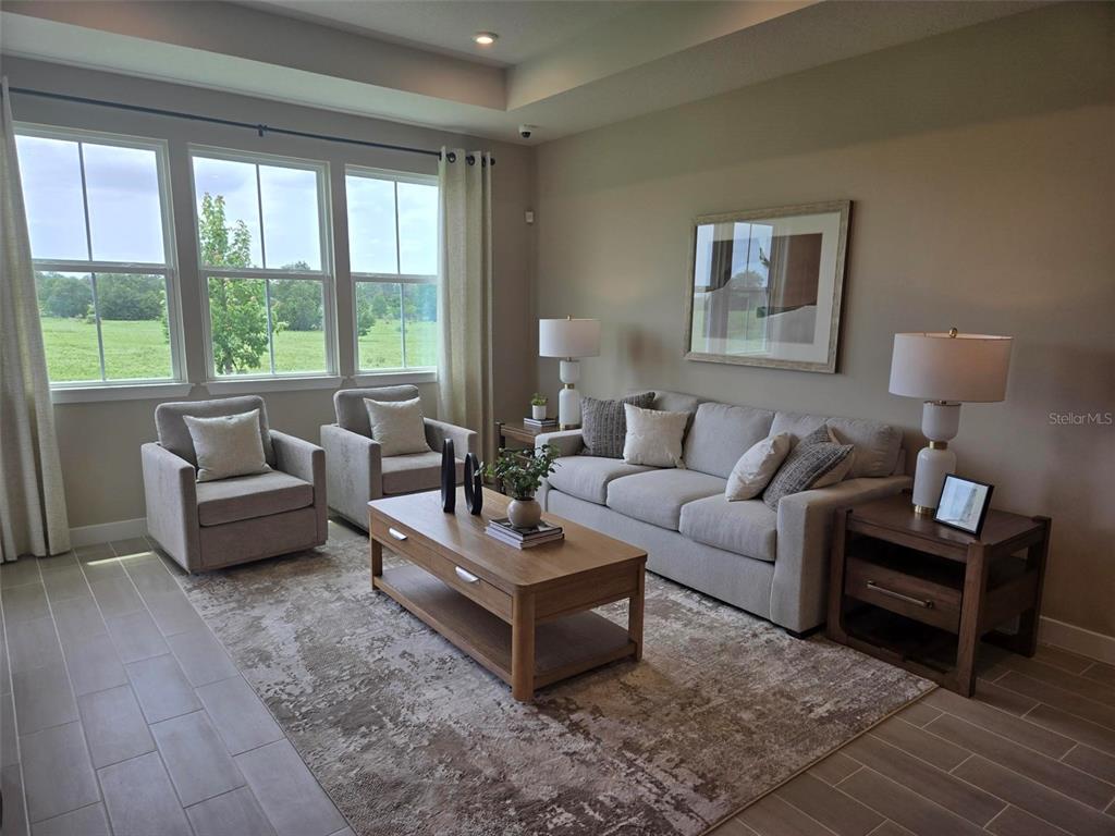 A living room features a beige sofa, two armchairs, a wooden coffee table, and large windows — 18857 EMERALD SUMMIT DRIVE, SPRING HILL, FL