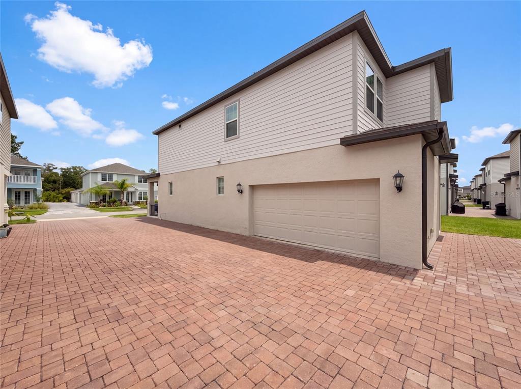 The exterior of a two-story house features a beige stucco garage and light-colored siding — 538 VENETIAN PALMS BOULEVARD, NEW SMYRNA BEACH, FL