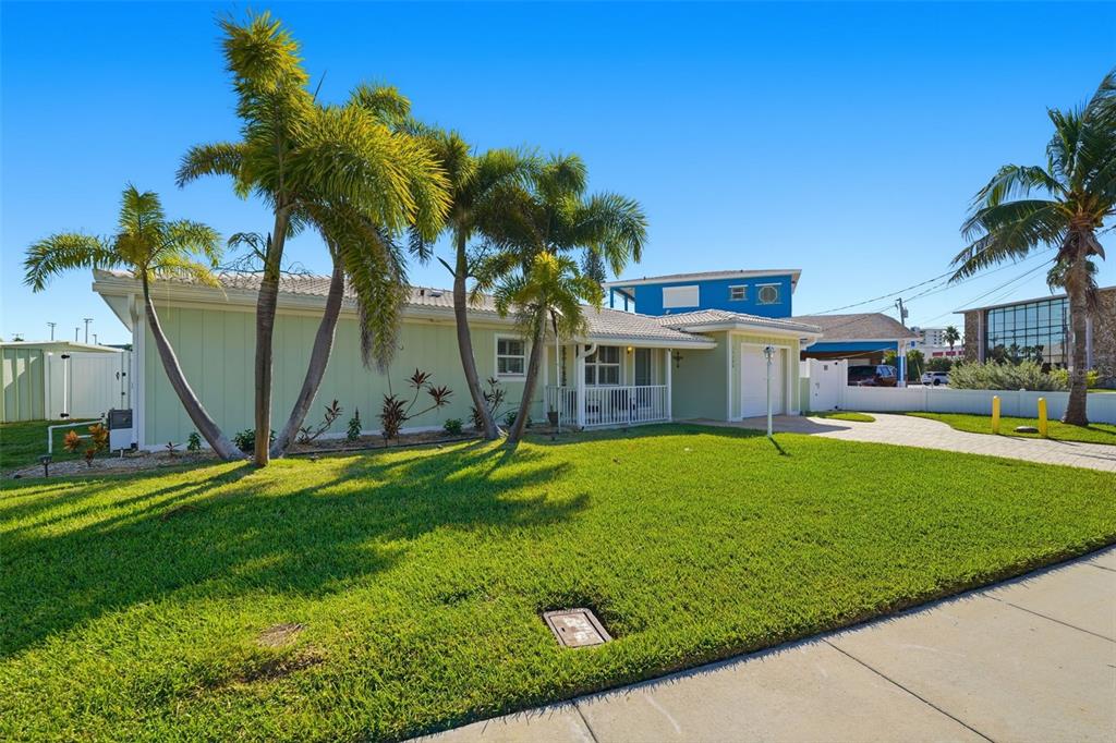 A light green single-story house with a white garage and palm trees in the yard — 15302 HARBOR DRIVE, MADEIRA BEACH, FL