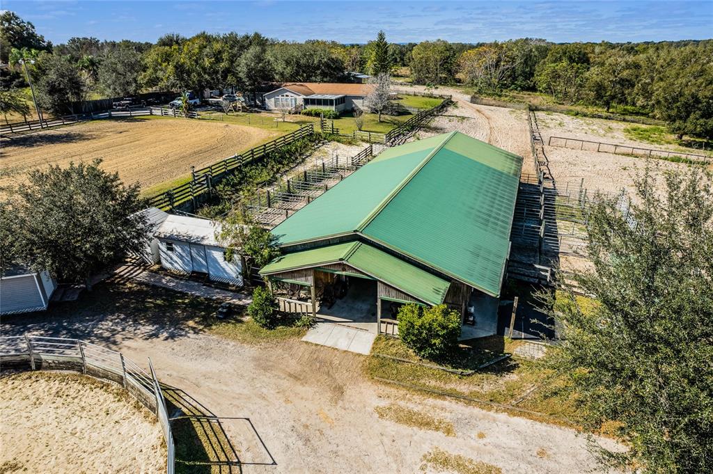 An aerial view shows a large barn with a green roof, paddocks, and a house — 1455 W KEENE ROAD, APOPKA, FL