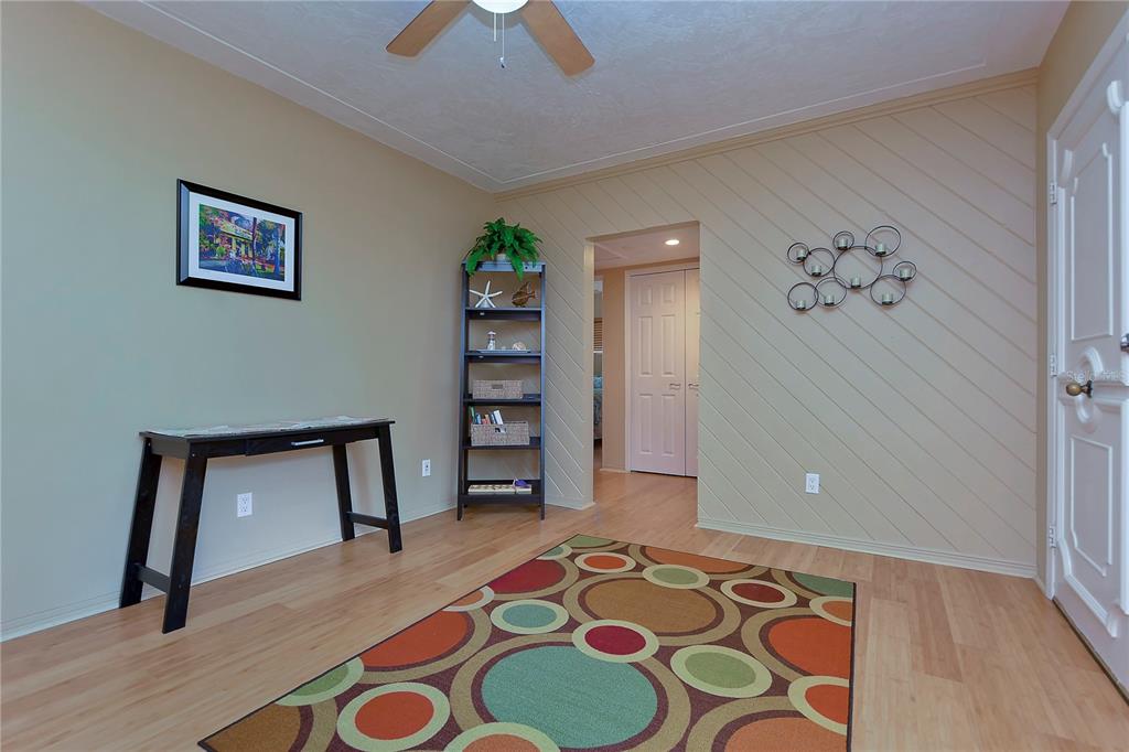 A room with light wood flooring, a patterned rug, a console table, and diagonal wall paneling — 5850 24TH AVENUE S, GULFPORT, FL