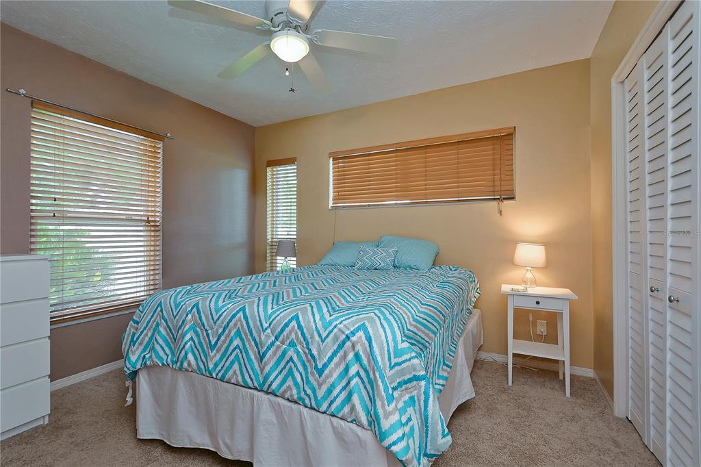 A bedroom features a bed with a blue chevron comforter, two windows, and white furniture — 5850 24TH AVENUE S, GULFPORT, FL