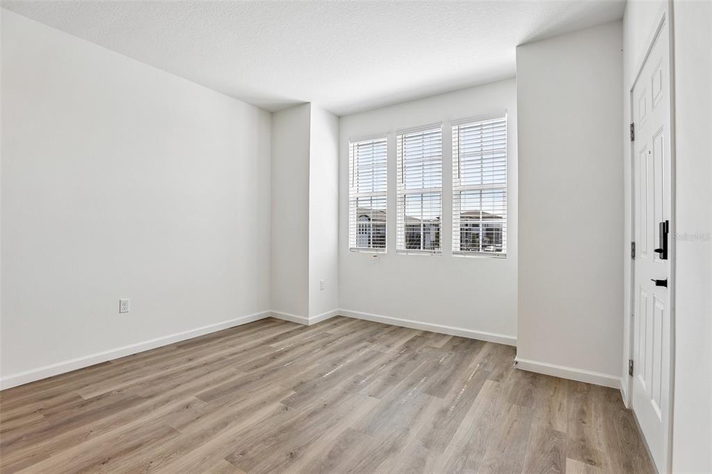 An empty room with white walls, wood-look flooring, and three windows with white blinds — 3075 SOLDIER CITY WAY UNIT 201, ST CLOUD, FL