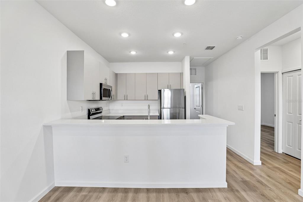 A kitchen features white cabinets, stainless steel appliances, and a breakfast bar with white countertops — 3075 SOLDIER CITY WAY UNIT 201, ST CLOUD, FL