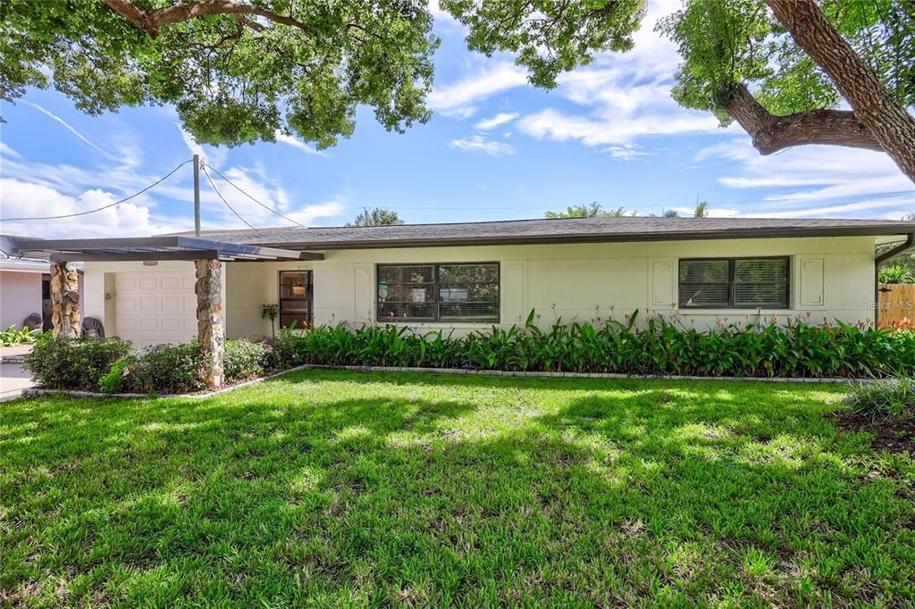 A single-story house with a stone-accented carport and a large front lawn under trees — 8532 KUMQUAT AVENUE, SEMINOLE, FL
