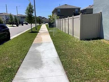 A sidewalk runs alongside a grassy lawn and a tall vinyl fence in a residential neighborhood — 11434 STONE PINE STREET, RIVERVIEW, FL