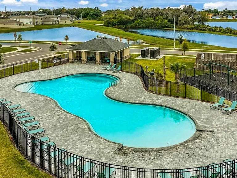 An aerial view shows a community swimming pool with a pavilion, lounge chairs, and playground — 11434 STONE PINE STREET, RIVERVIEW, FL