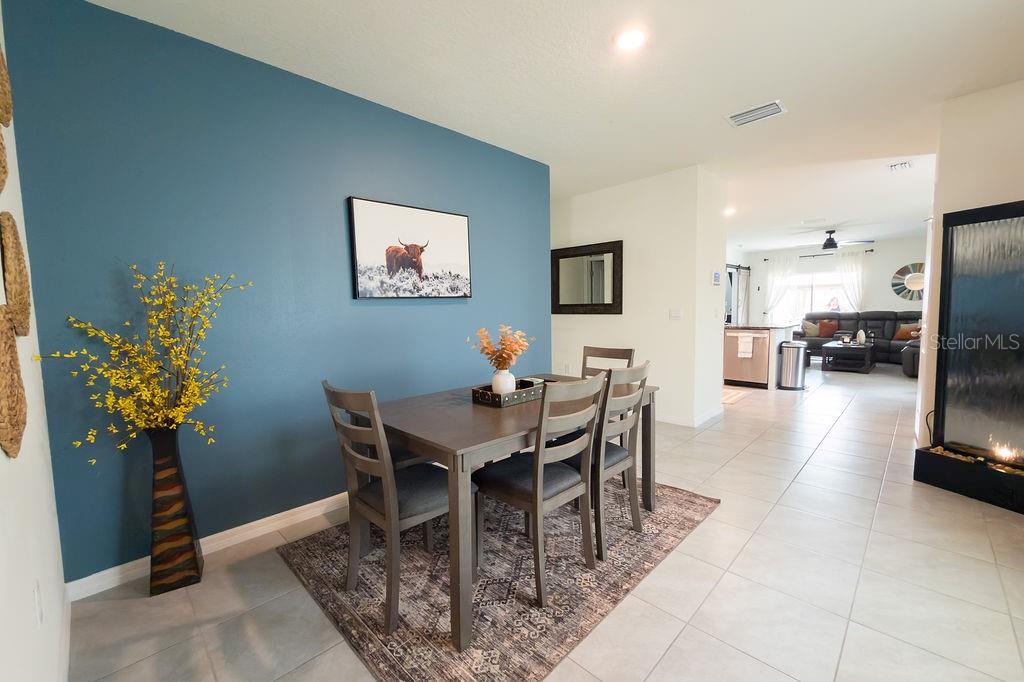 A dining area with a blue accent wall, wooden table, and tile flooring — 17014 BLISTER WING DRIVE, WIMAUMA, FL