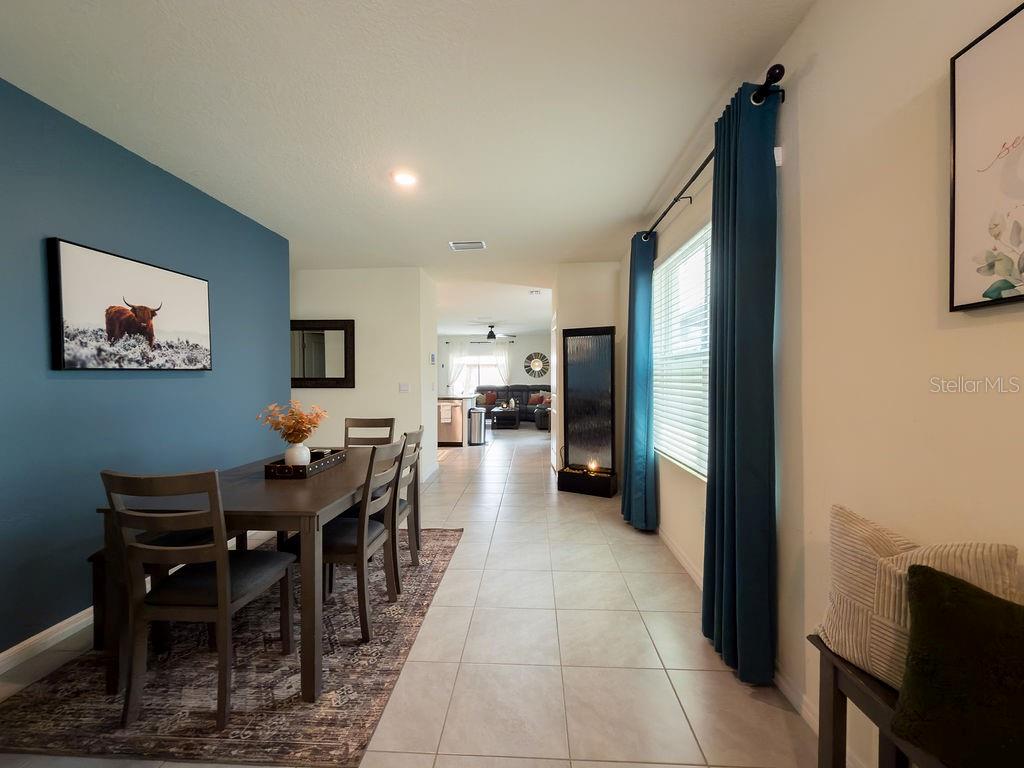 A dining area with a blue accent wall leads into an open-concept living space — 17014 BLISTER WING DRIVE, WIMAUMA, FL