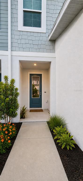 A concrete walkway leads to a blue front door under a covered entryway — 8695 CANYON CREEK TRAIL, PARRISH, FL