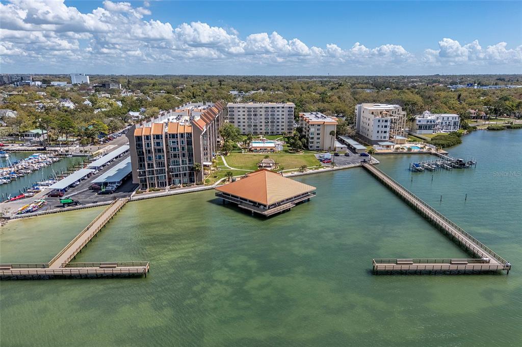 An aerial view shows a waterfront condominium complex with a pier and a central pavilion — 620 EDGEWATER DRIVES UNIT 103, DUNEDIN, FL