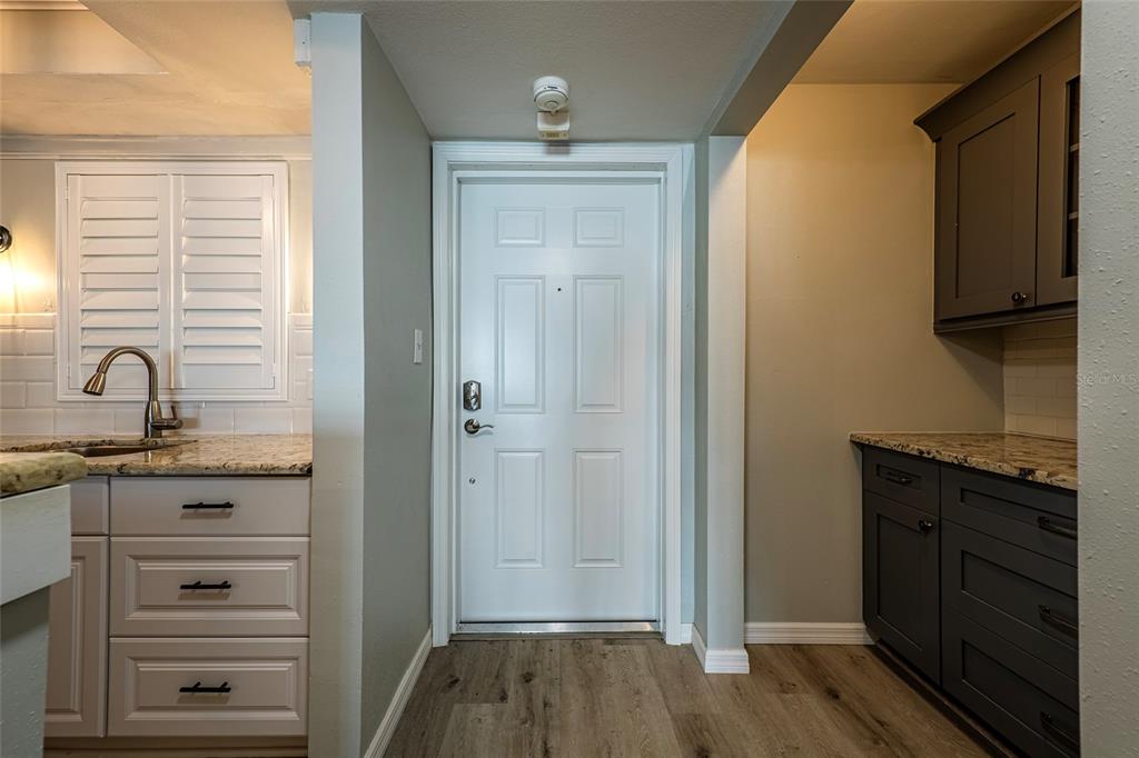 A kitchen features light cabinets on the left, dark cabinets on the right, and a door — 620 EDGEWATER DRIVES UNIT 103, DUNEDIN, FL
