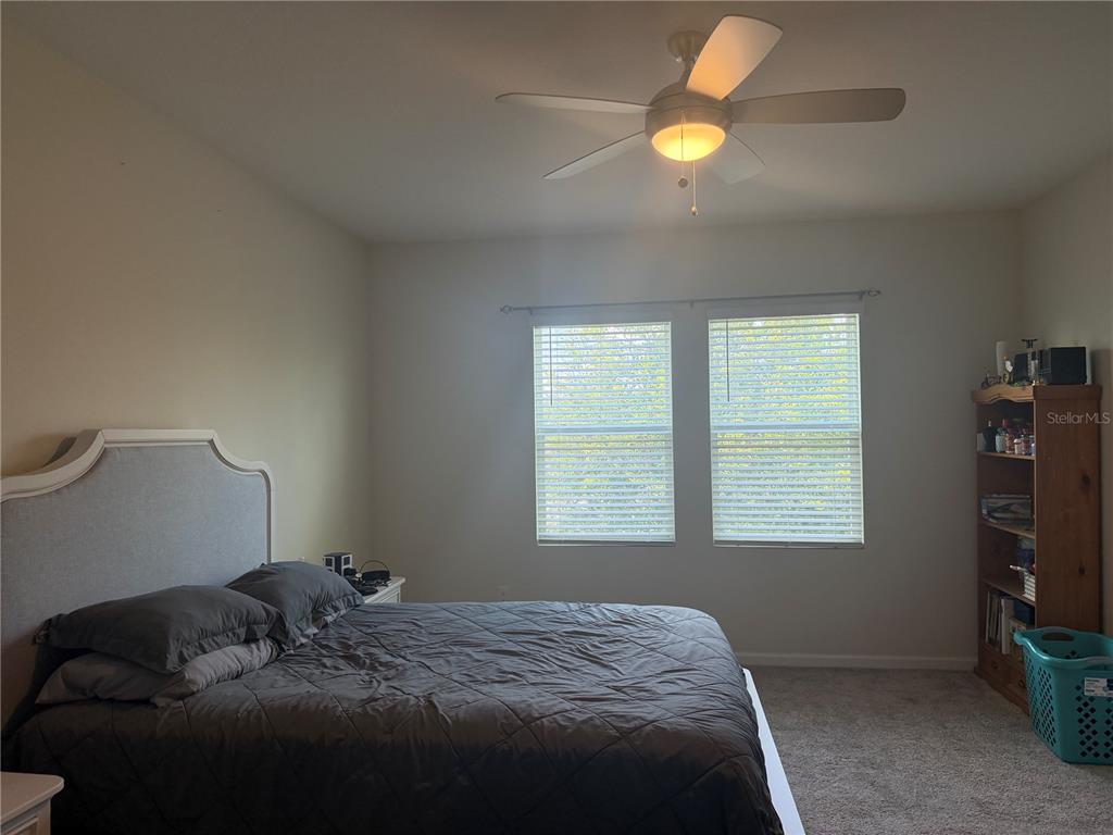 A bedroom features a gray upholstered headboard, a ceiling fan, two windows, and a bookshelf — 9896 RED EAGLE DRIVE, ORLANDO, FL