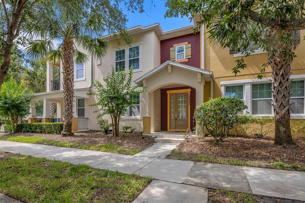 A two-story townhouse with a tan facade, a maroon accent wall, and a front porch — 12357 VIA DERNA PLACE, WINDERMERE, FL