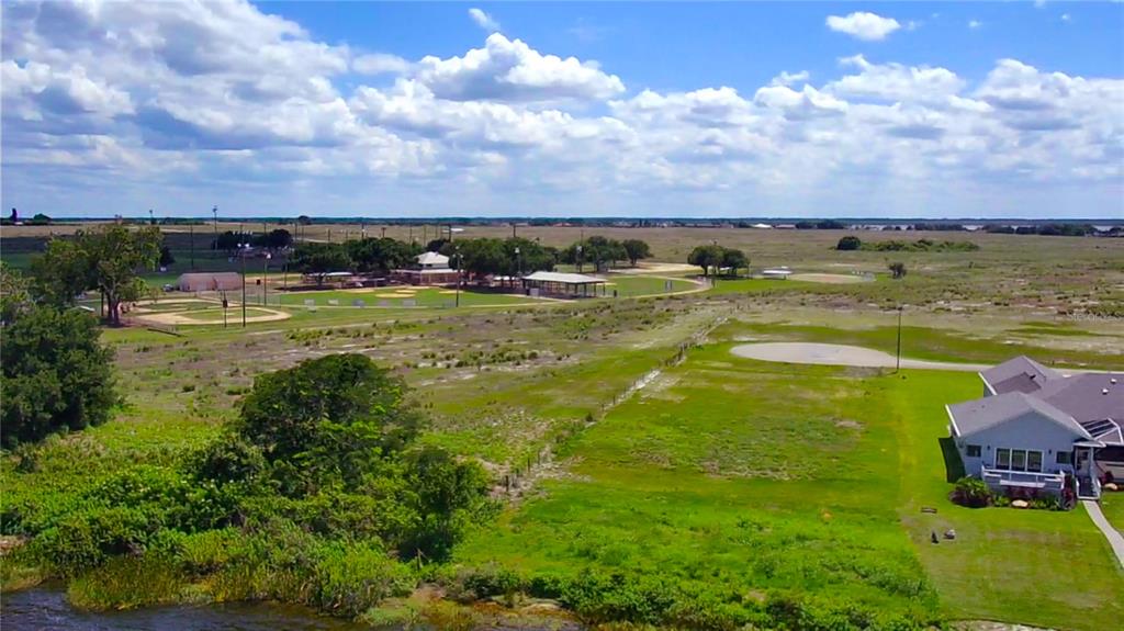 An aerial view shows a house next to a large open field and baseball diamonds — 466 SUNSET POINTE DRIVE, LAKE PLACID, FL