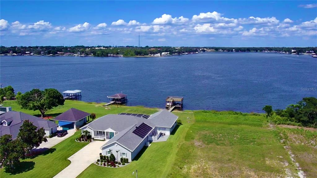An aerial view shows a house with solar panels, a lawn, and a private boat dock — 466 SUNSET POINTE DRIVE, LAKE PLACID, FL