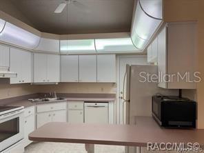 A kitchen with white cabinets, laminate countertops, a white stove, and a microwave — 824 WINDERMERE BOULEVARD, INVERNESS, FL