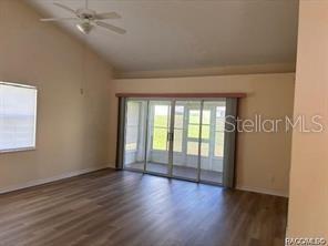 A living room with light-colored walls, wood-look flooring, a ceiling fan, and sliding glass doors — 824 WINDERMERE BOULEVARD, INVERNESS, FL