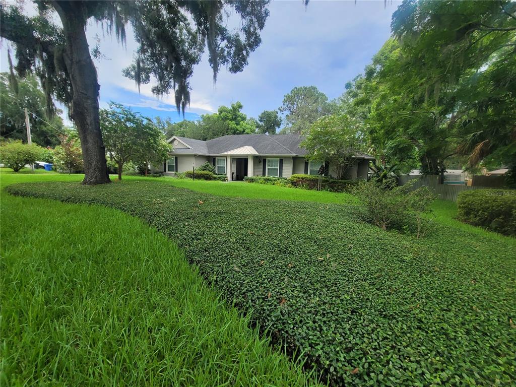 A single-story house with a gray exterior, dark shutters, and a metal-roofed entryway — 1508 ECKLES DRIVE, TAMPA, FL