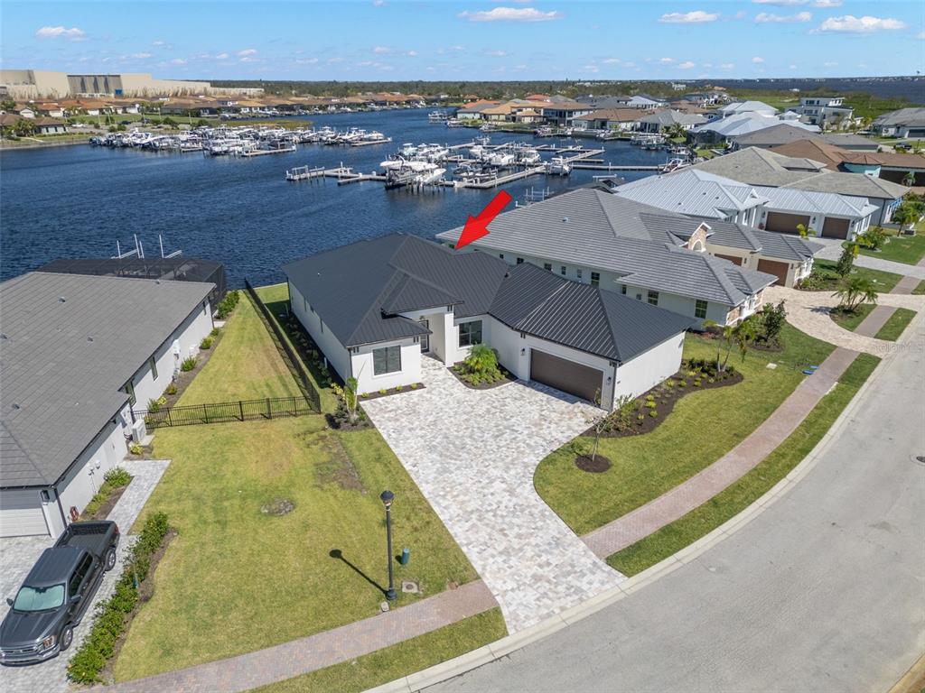 An aerial view shows a modern house with a dark metal roof and paver driveway — 1810 4TH STREET E, PALMETTO, FL