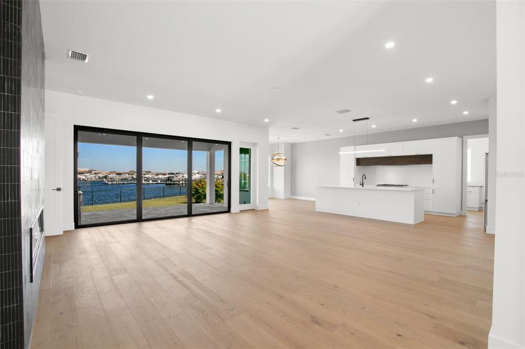 An open-concept living area with light wood floors, a modern kitchen, and sliding glass doors — 1810 4TH STREET E, PALMETTO, FL